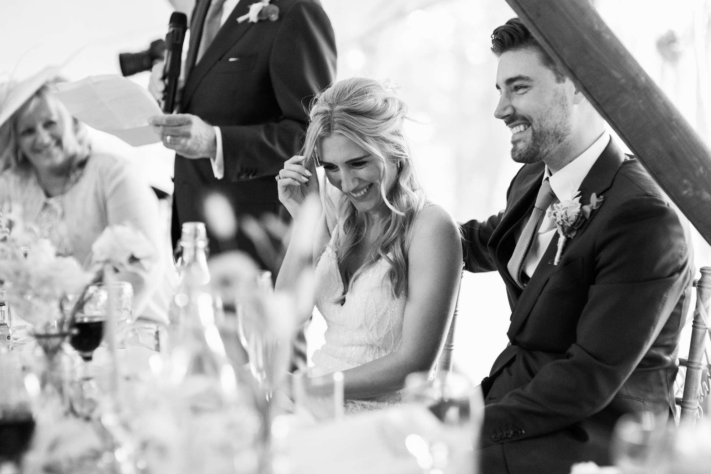 Bride laughs during the speeches at her festival themed wedding at The Wilderness Reserve in Kent