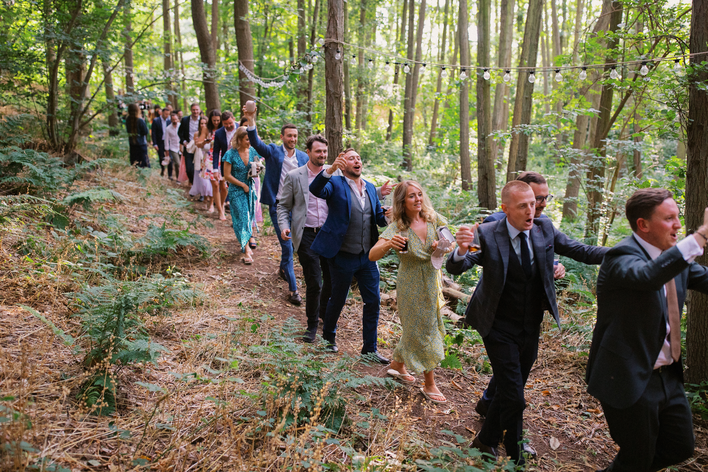 Guests walk through the woods at a festival themed wedding at The Wilderness Reserve in Kent