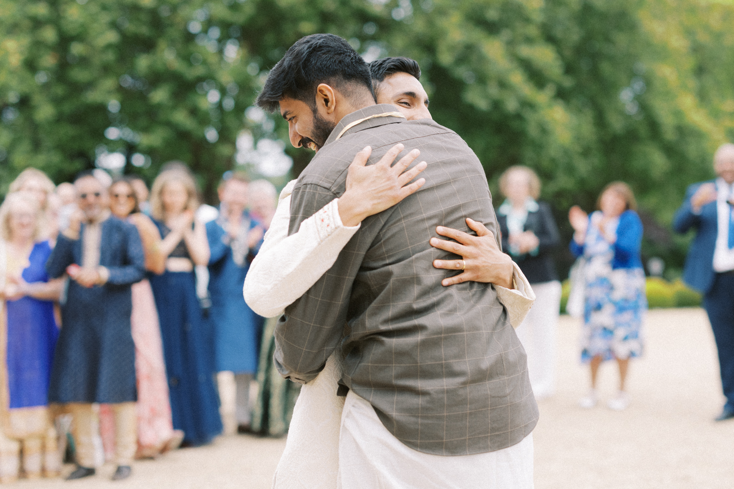 Natural wedding photography of groom embracing guest on wedding day