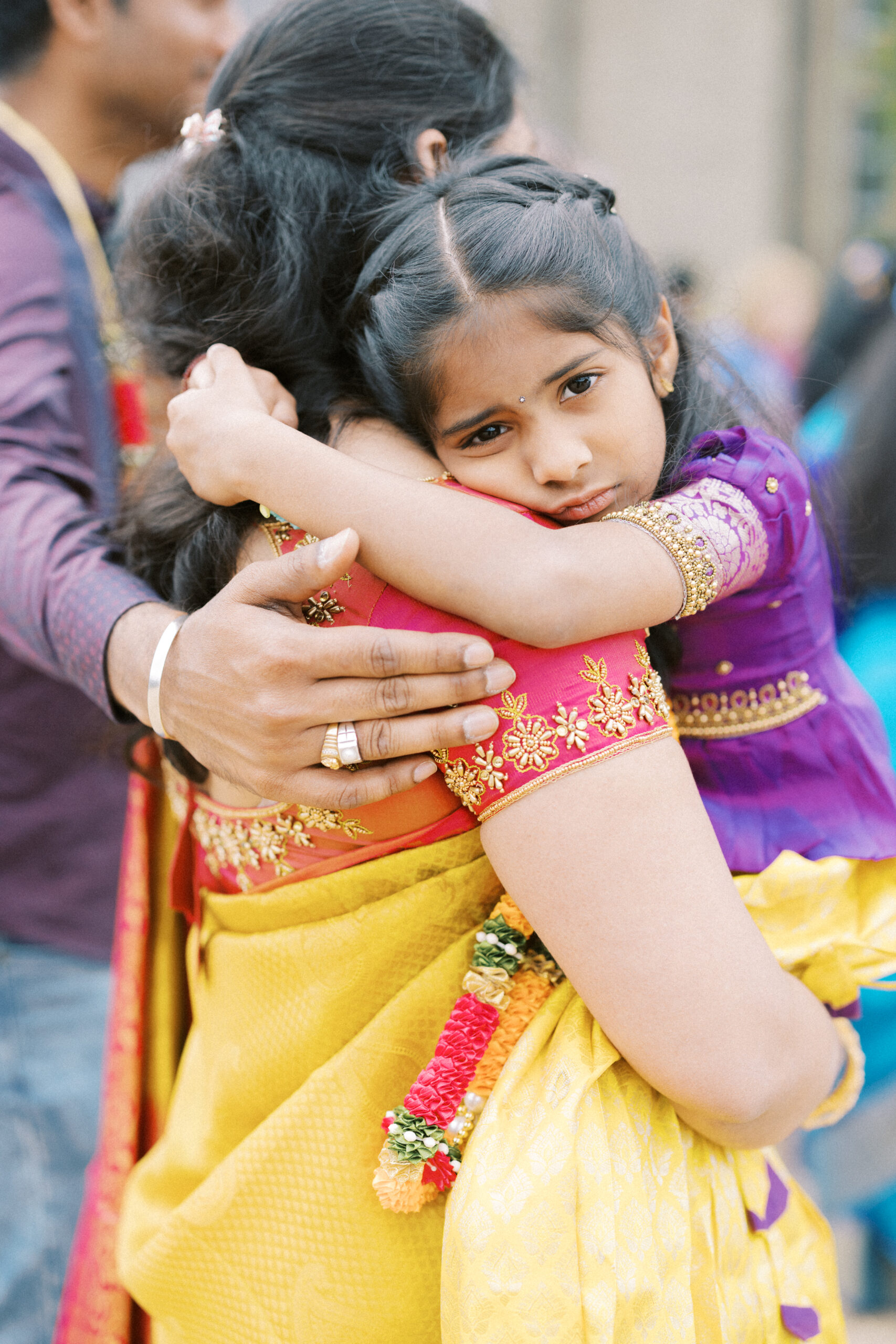 Candid photograph of a girl in her mums arms at an Indian wedding