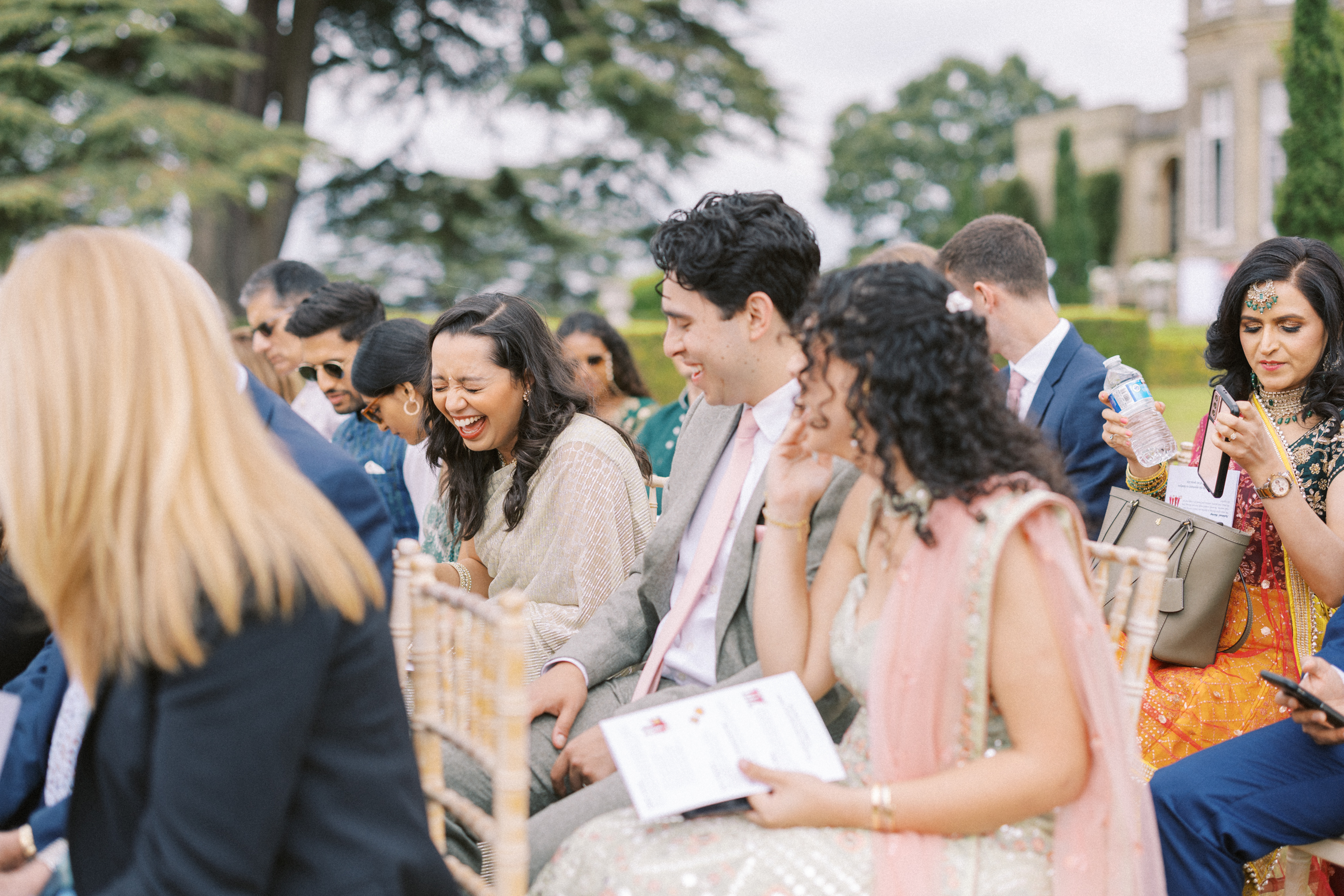 Guests laugh waiting for the bride to arrive at Hedsor House Wedding