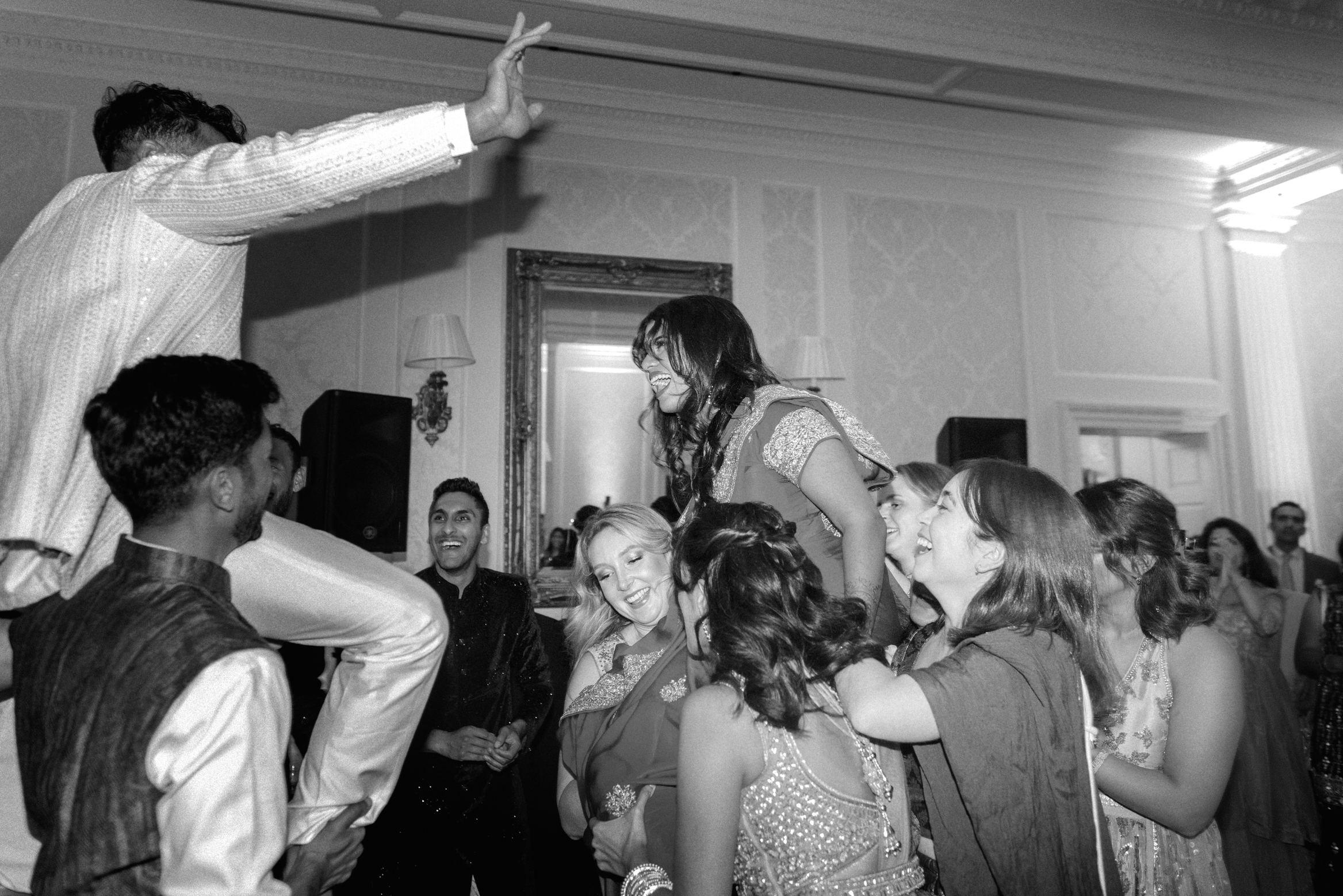 bride and groom get lifted up by guests at their Indian wedding at Hedsor House