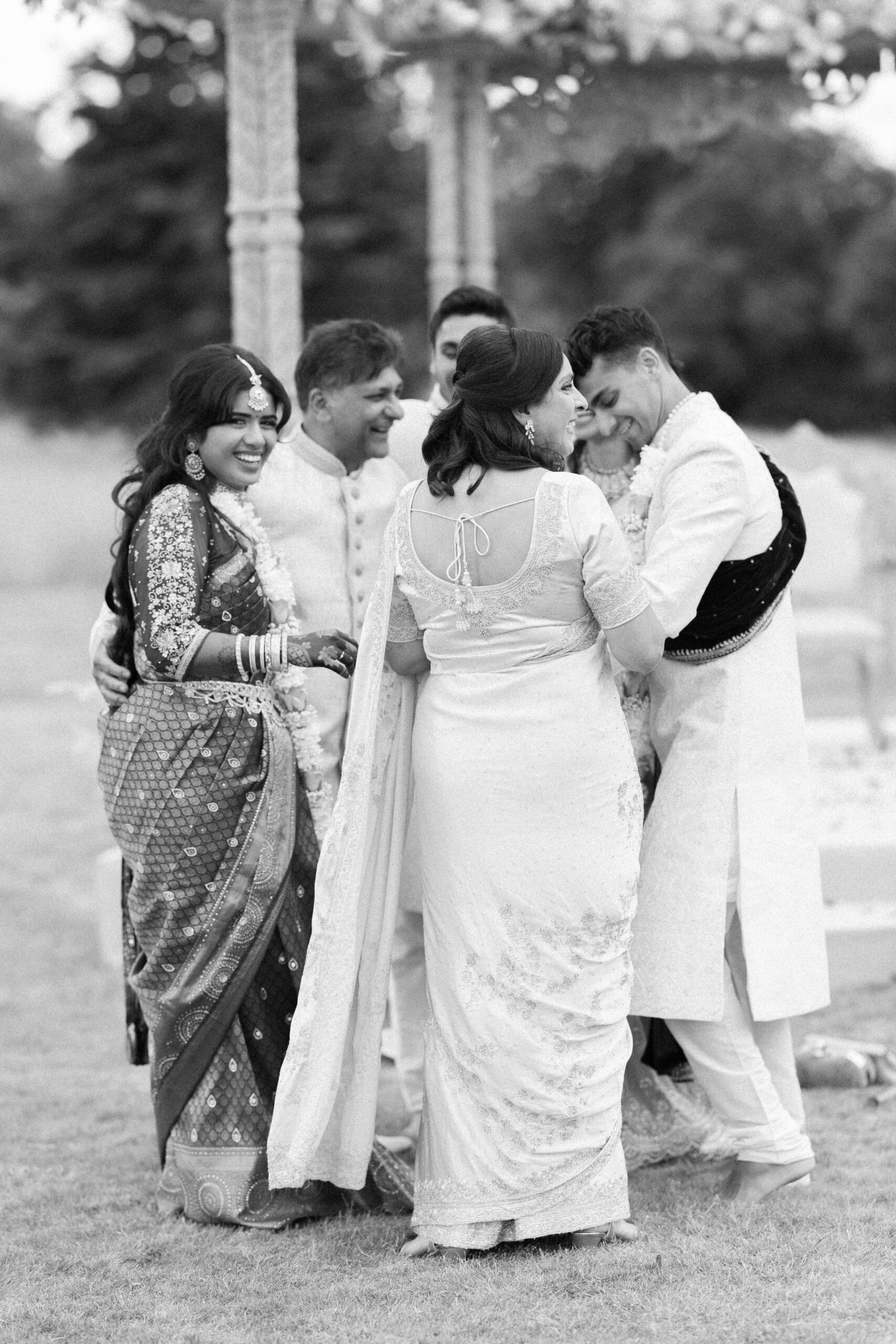 Bride and groom embrace their family at indian wedding