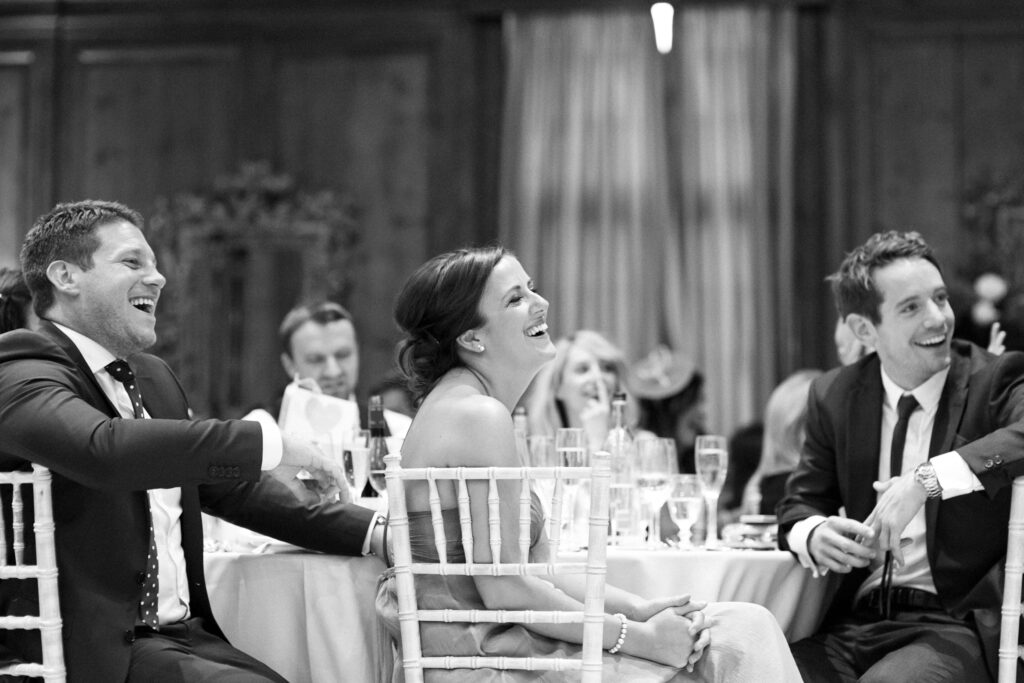 Guests laugh during wedding speeches in the ballroom at Hedsor House