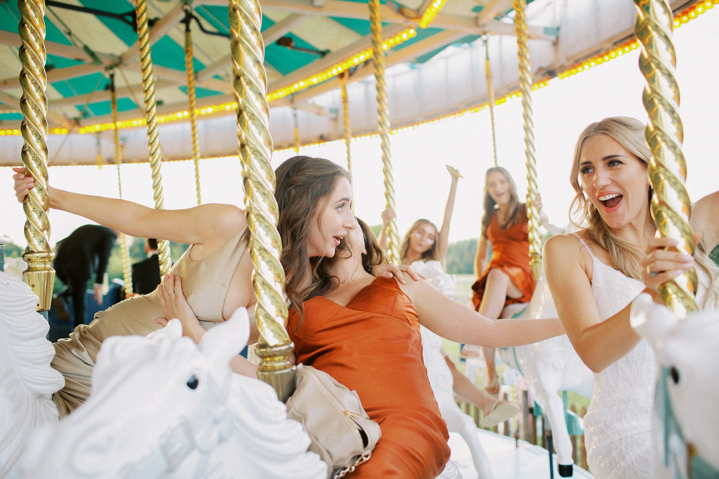 Bride and her bridesmaids laugh on the Preston Court Wedding Venues carousel at festival themed wedding