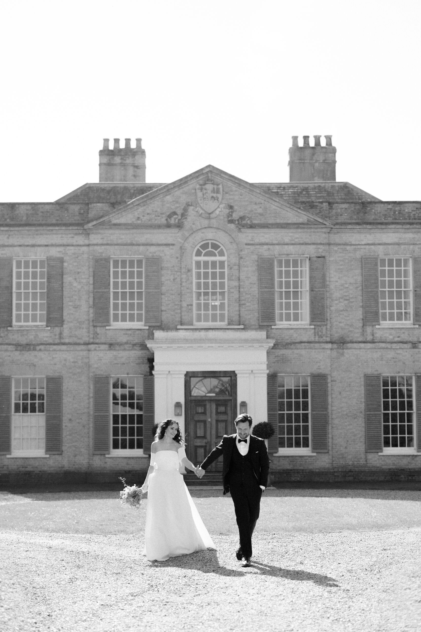 Couple walk in front of Findon Place Stately home on their wedding day
