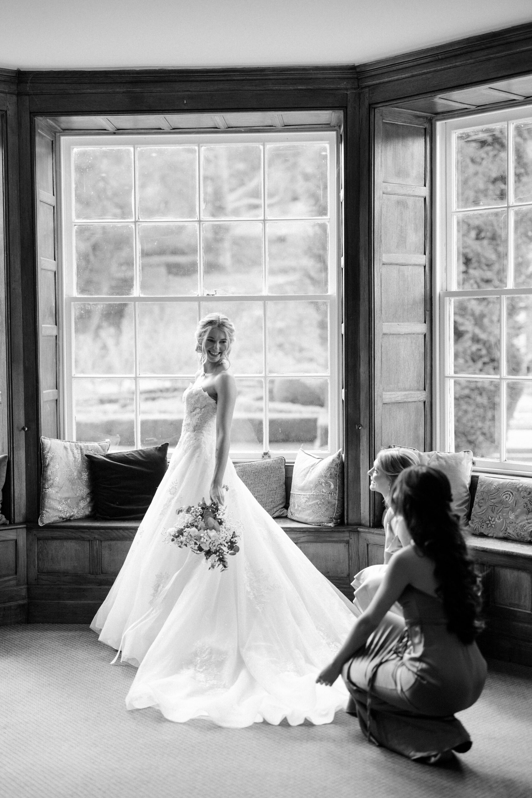 Bridesmaids helping the bride into her dress at country house venue Wotton House