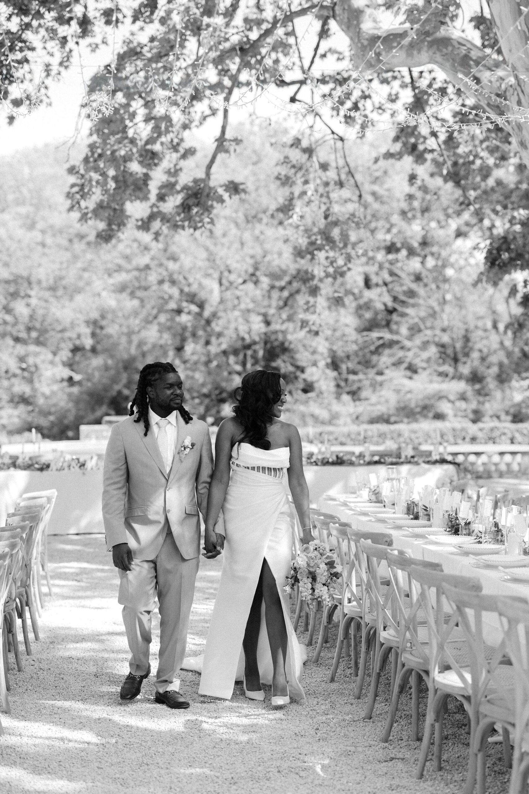 Bride and groom admire breakfast tables set under twinkling fairy lights, outdoors at Château de Valmousse, Provence
