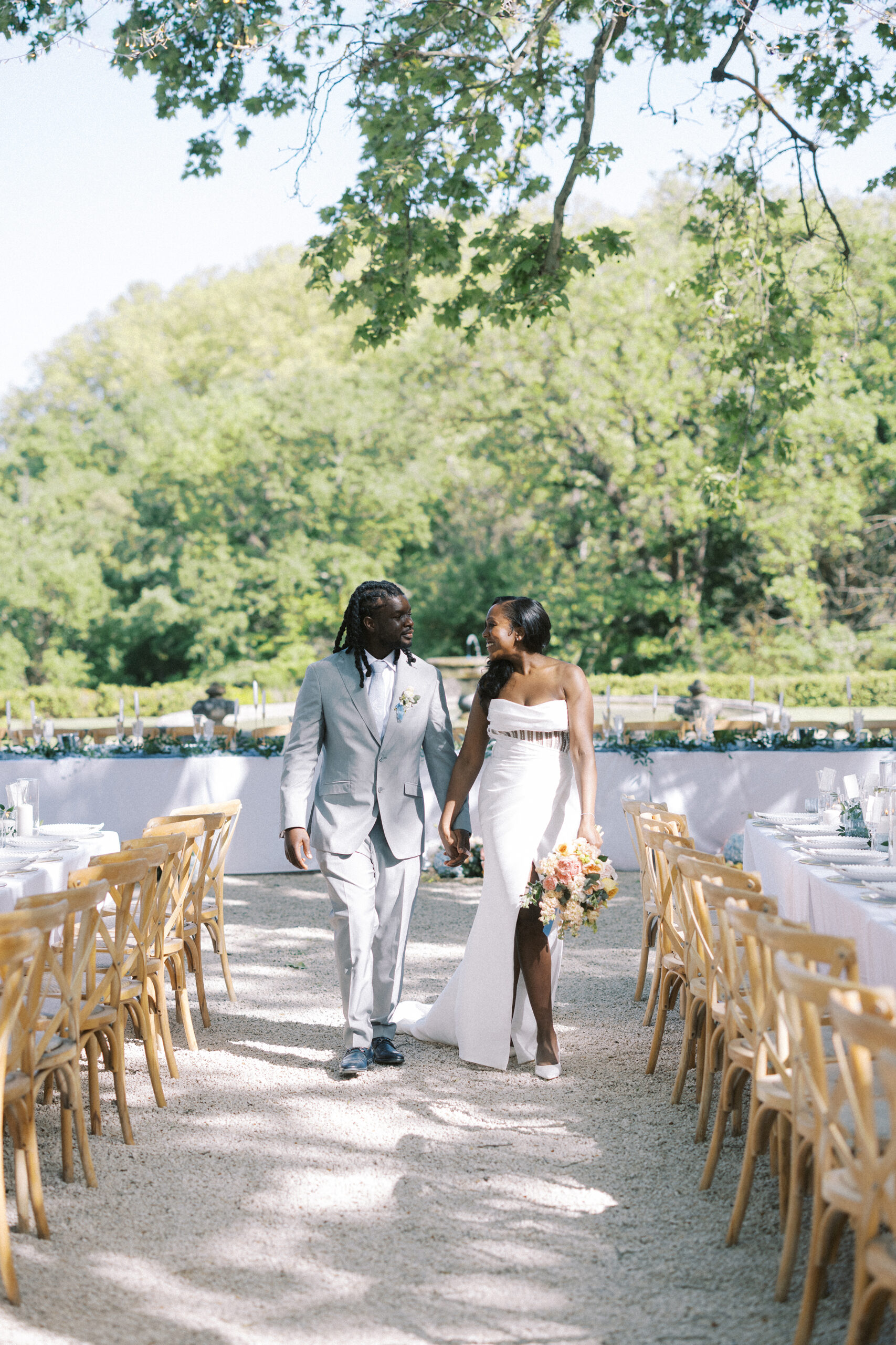 Bride and groom walk through breakfast tables set under twinkling fairy lights, outdoors at Château de Valmousse, Provence