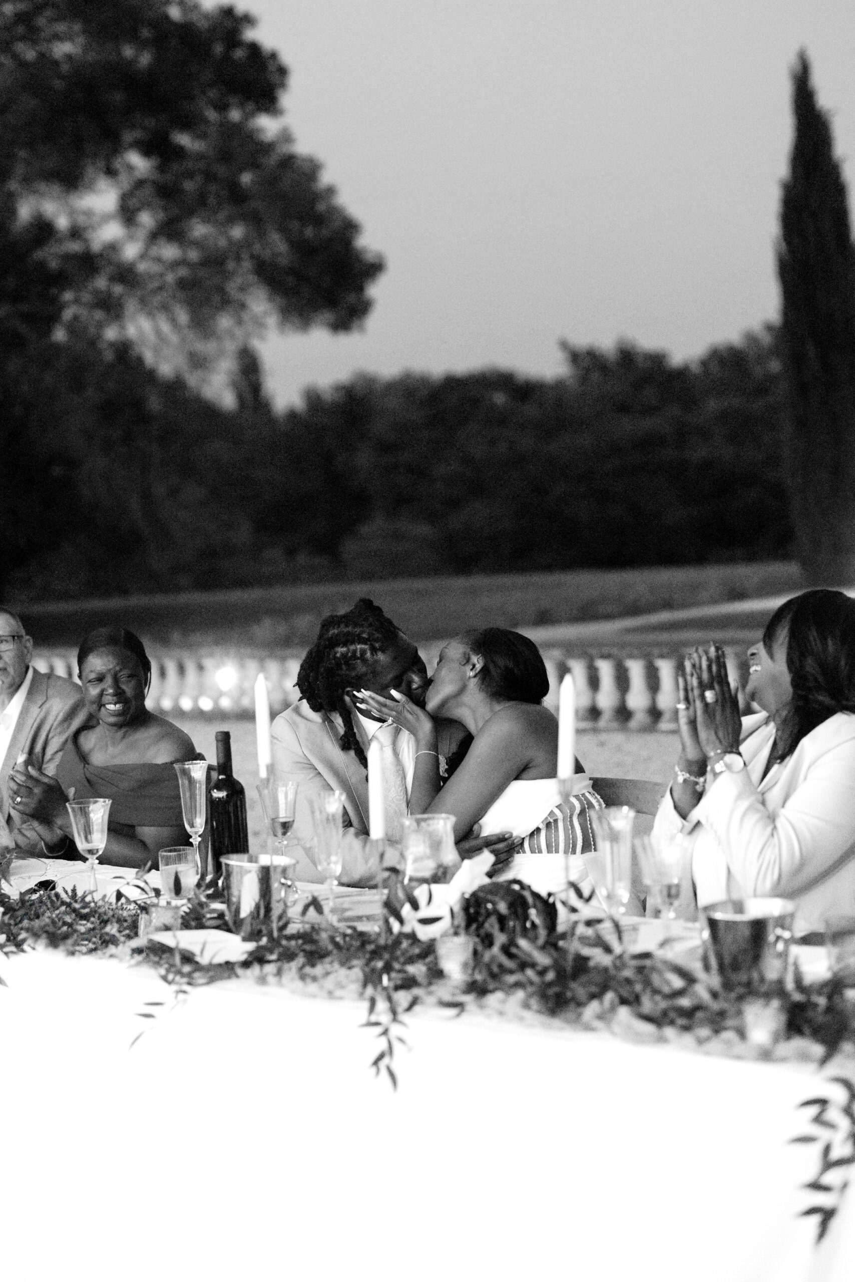 Bride and groom kiss at wedding breakfast table after speeches