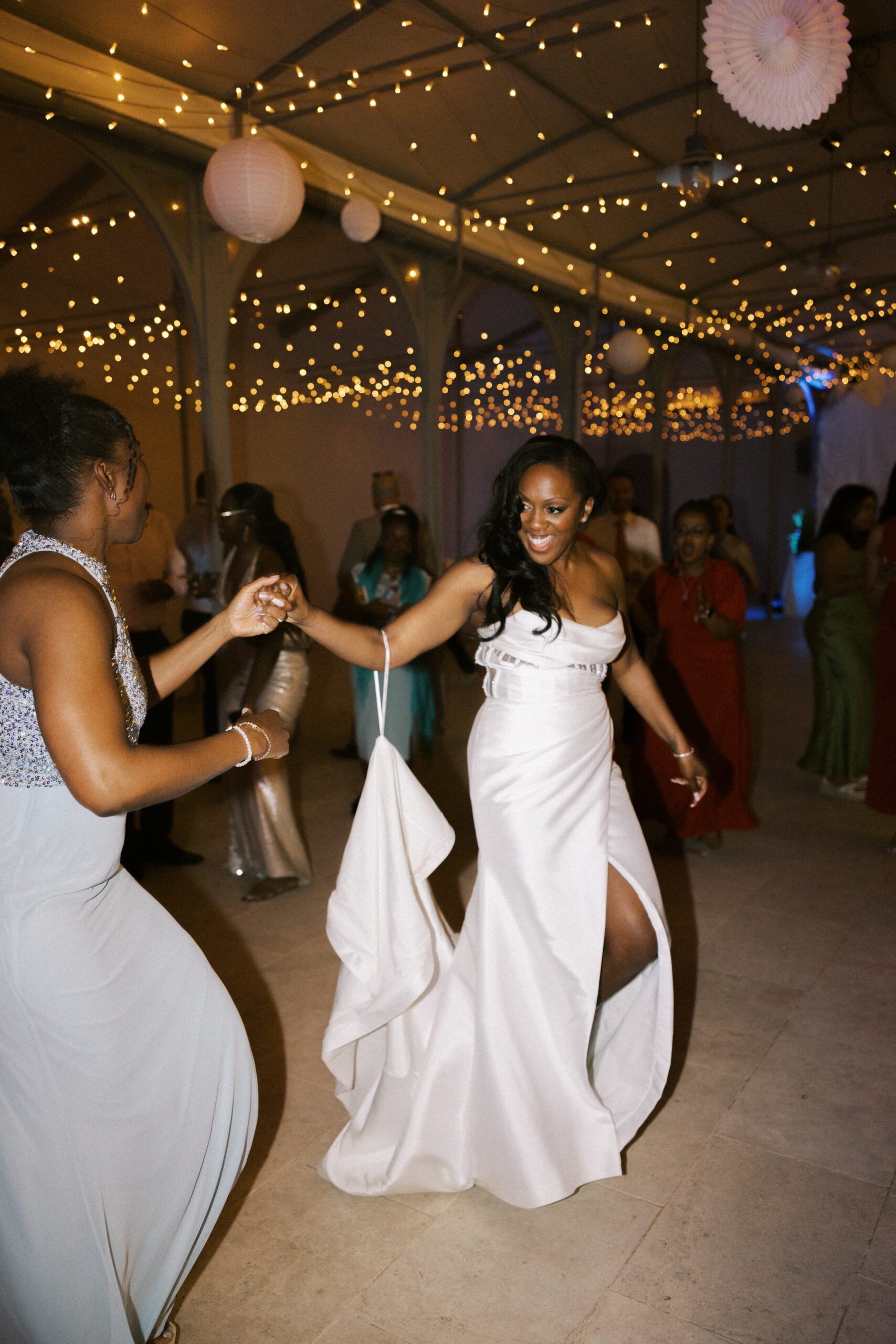 Bride dancing under string lights at Chateau de Valmousse, captured by a French destination wedding photographer
