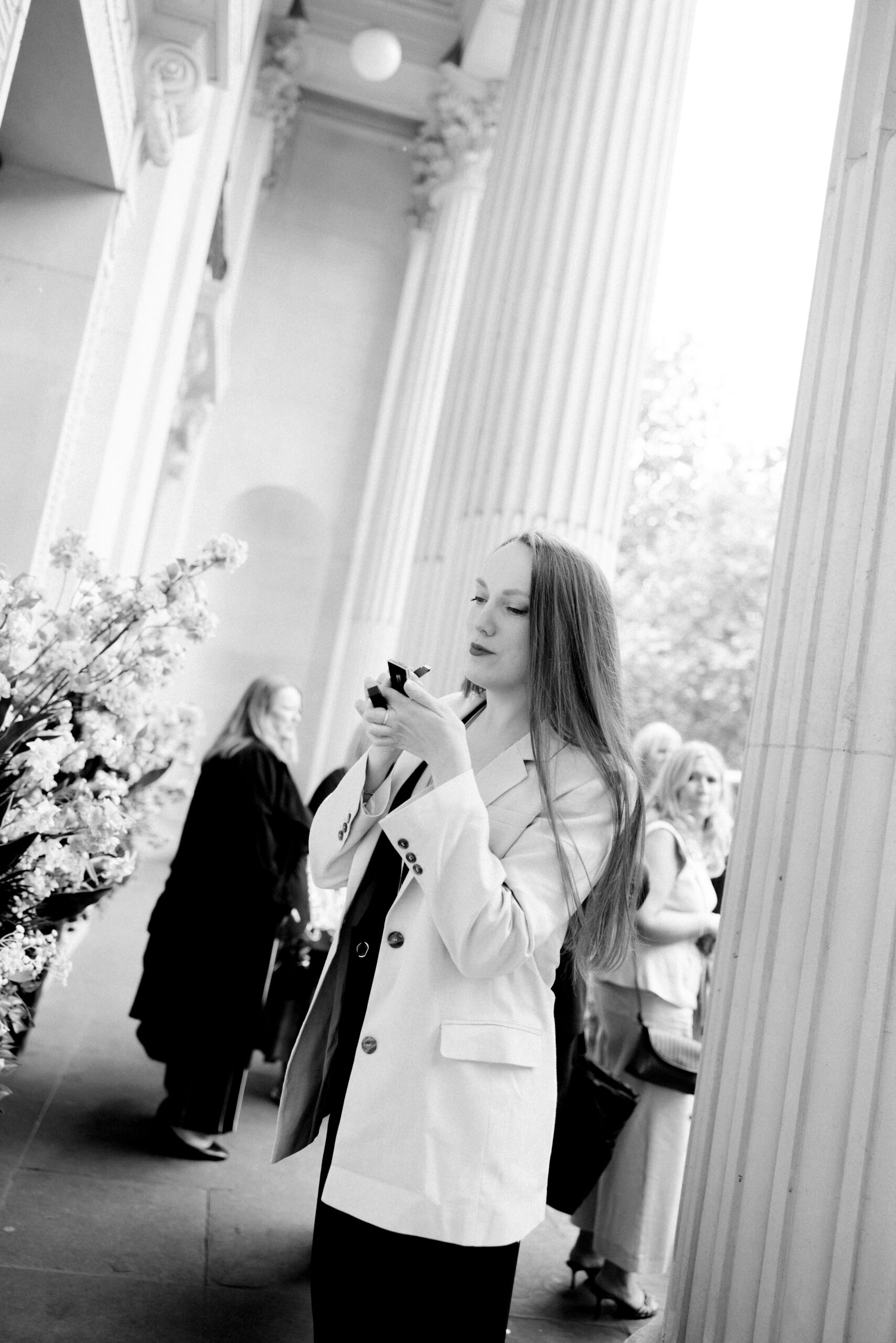Guest applies lipstick before her friends wedding at Old Marylebone Town Hall